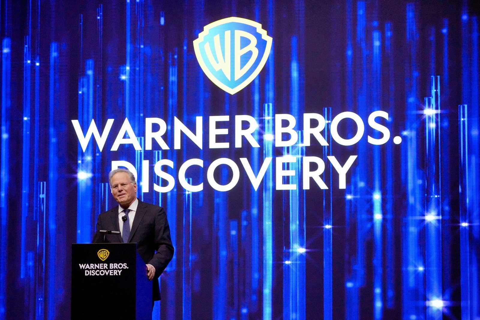 David Zaslav speaks in front of Warner Bros. Discovery logo on blue drape